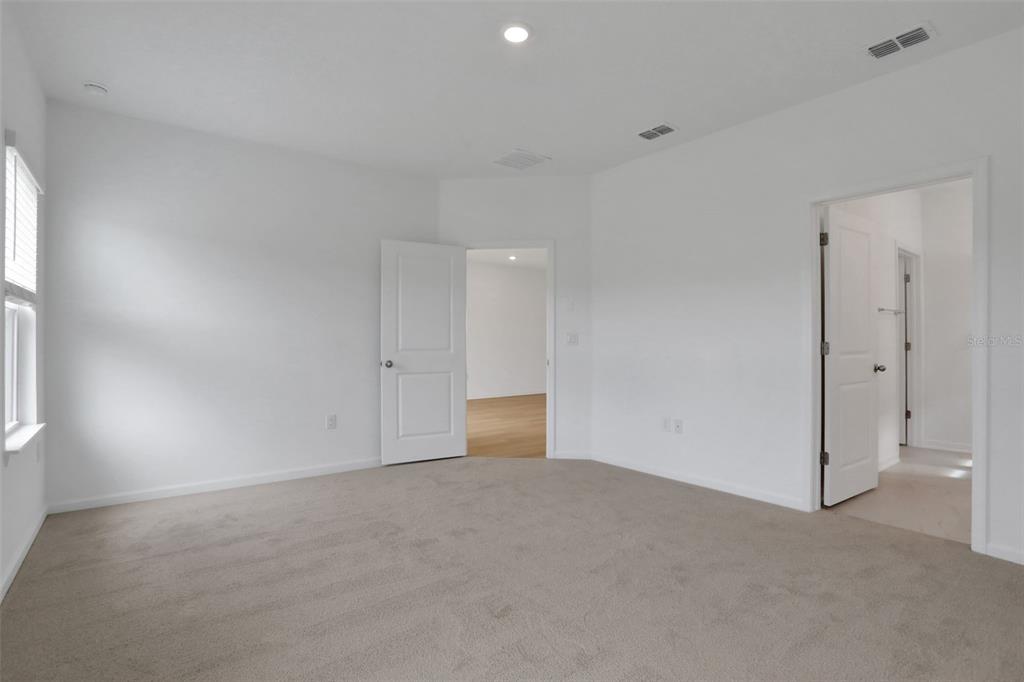 A carpeted bedroom features white walls, two open doorways, and a window with blinds — 204 DONOVAN DRIVE, ST AUGUSTINE, FL