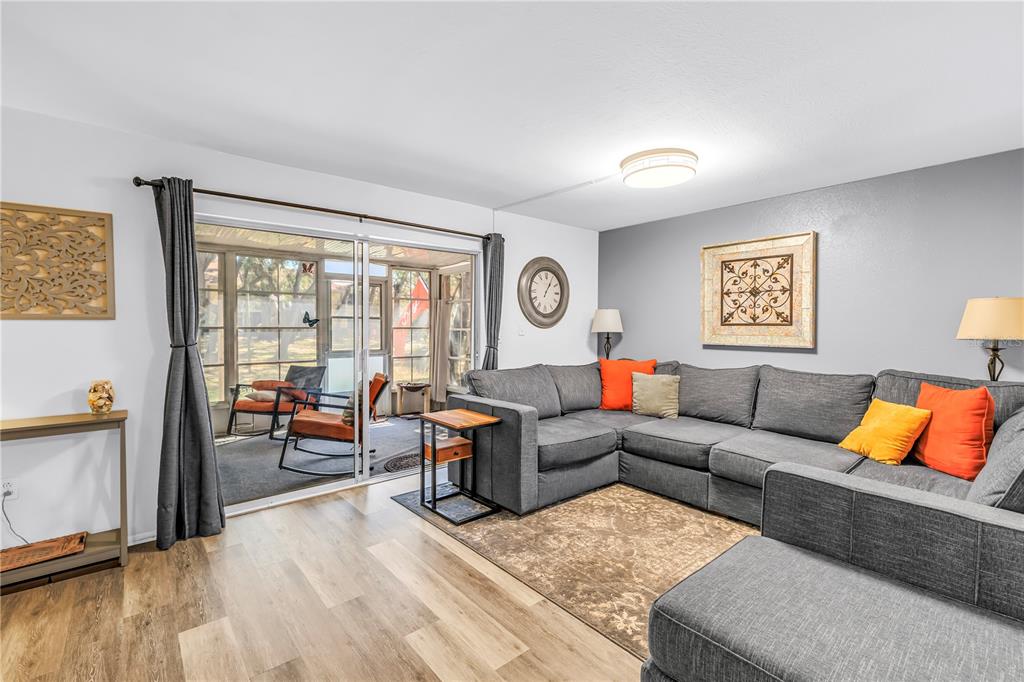 A living room features a gray sectional sofa, a brown area rug, and sliding glass doors — 3620 41ST WAY S UNIT F, ST PETERSBURG, FL
