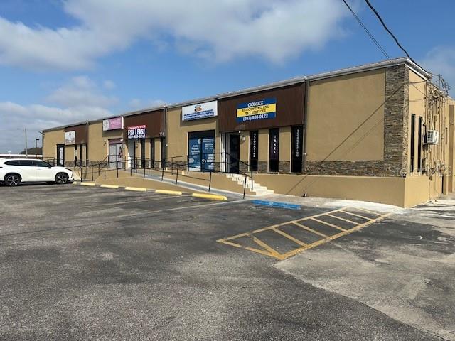 A tan commercial strip mall building with a parking lot and a white car — 1011 W LANCASTER ROAD, ORLANDO, FL
