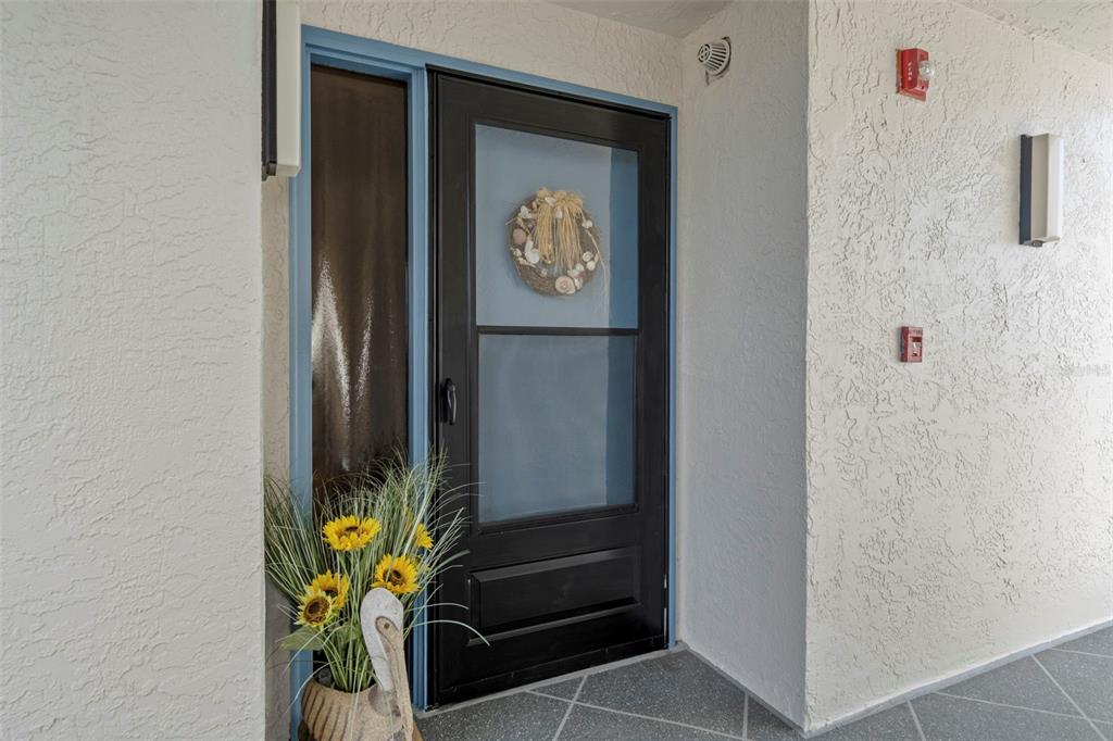 A black storm door with a wreath stands at the entrance of a stucco building — 4650 BAY BOULEVARD UNIT 1048, PORT RICHEY, FL