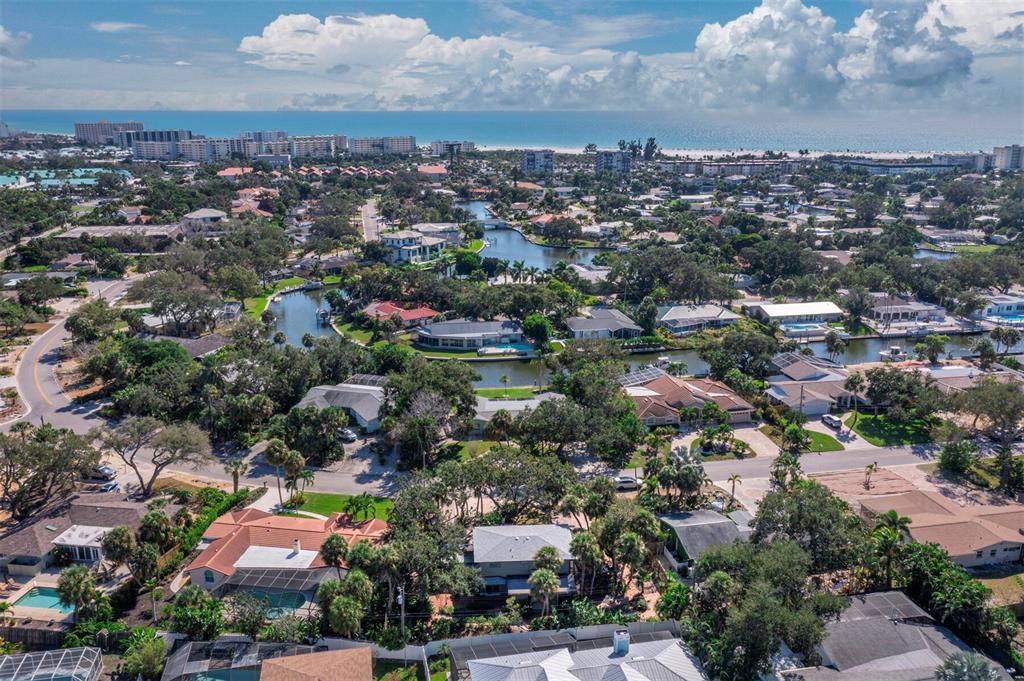 An aerial view shows a residential neighborhood with houses, swimming pools, and winding canals — 5451 SHADOW LAWN DRIVE, SARASOTA, FL