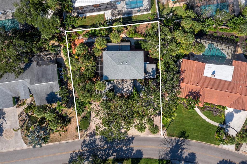 An aerial view shows a house with a gray roof surrounded by trees and landscaping — 5451 SHADOW LAWN DRIVE, SARASOTA, FL