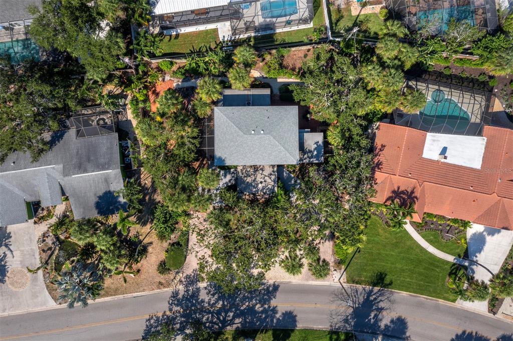 An aerial view shows a house with a gray roof surrounded by trees and landscaping — 5451 SHADOW LAWN DRIVE, SARASOTA, FL