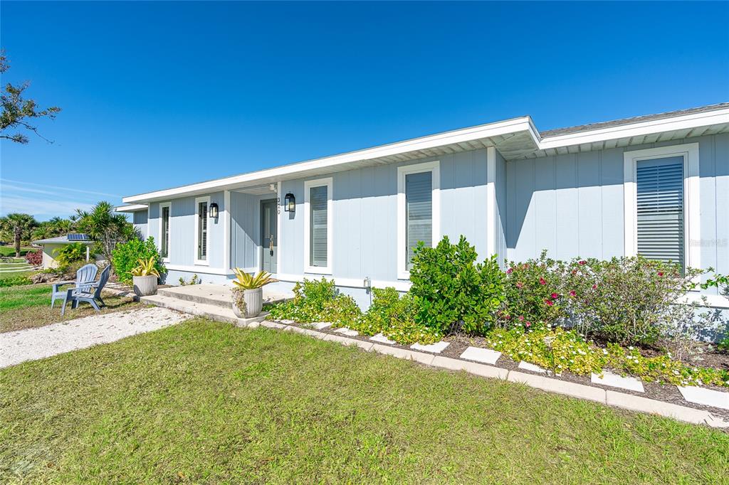 A light blue single-story house with white trim, a front porch, and landscaped yard — 320 ANCHOR ROW, PLACIDA, FL