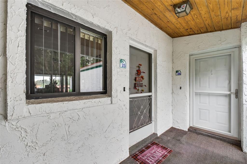 An exterior view shows two adjacent apartment entry doors with screen doors and a window — 4729 CASABLANCA UNIT C25, SEBRING, FL