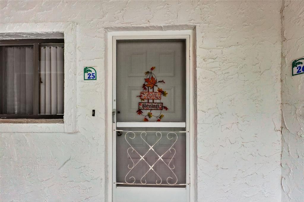 A white stucco exterior features a front door with a screen and fall-themed decoration — 4729 CASABLANCA UNIT C25, SEBRING, FL
