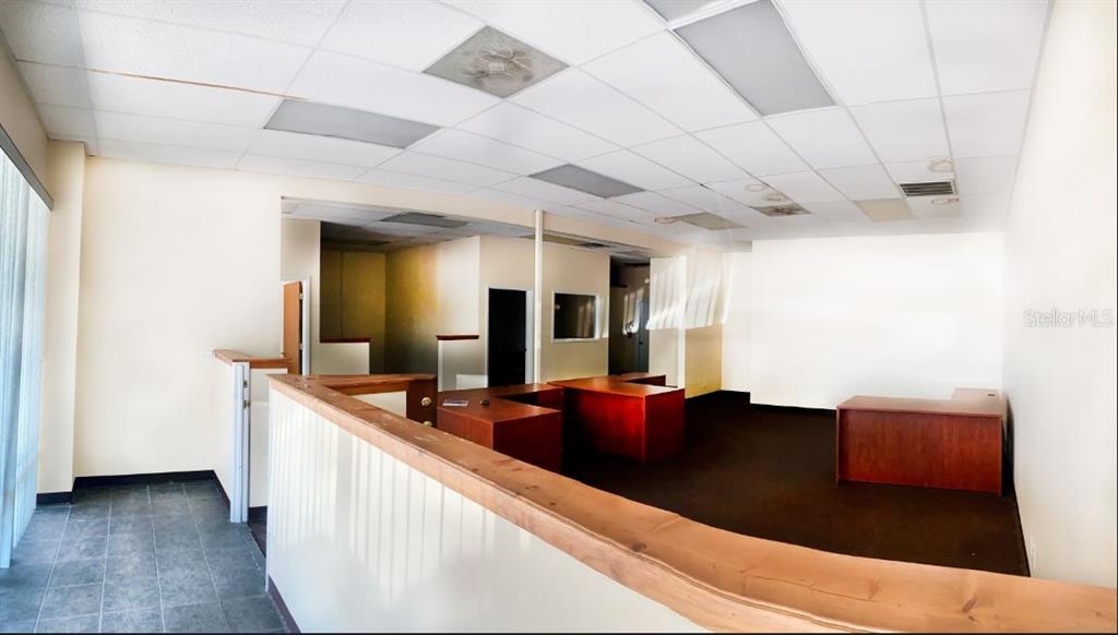 An office interior features a drop ceiling, dark carpet, and a wooden reception counter — 9701 N 66TH STREET, PINELLAS PARK, FL