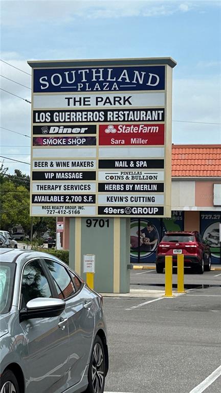 A large, multi-tenant business directory sign stands in a parking lot in front of a plaza — 9701 N 66TH STREET, PINELLAS PARK, FL