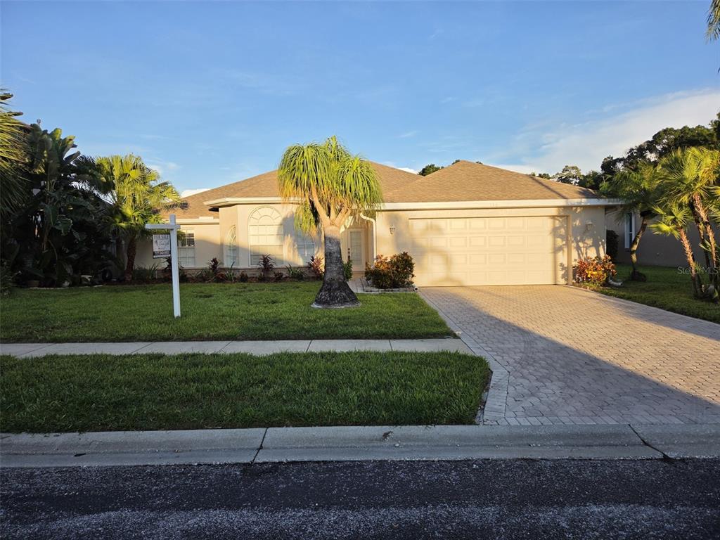 A beige house with a two-car garage and a paved driveway sits behind palm trees — 740 SALT LAKE DRIVE, TARPON SPRINGS, FL