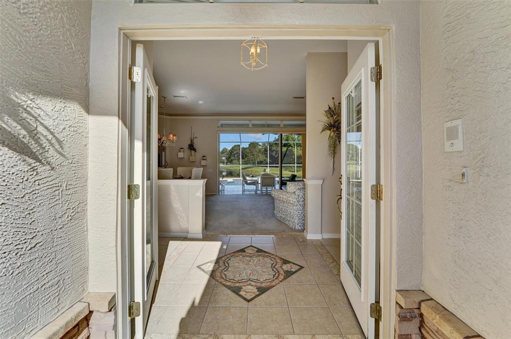 A dining area and living space feature carpeted floors, a chandelier, and sliding glass doors — 740 SALT LAKE DRIVE, TARPON SPRINGS, FL