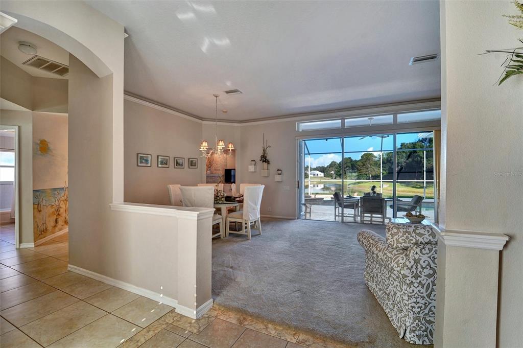 A dining area with a glass table and chairs overlooks a pool and lake view — 740 SALT LAKE DRIVE, TARPON SPRINGS, FL