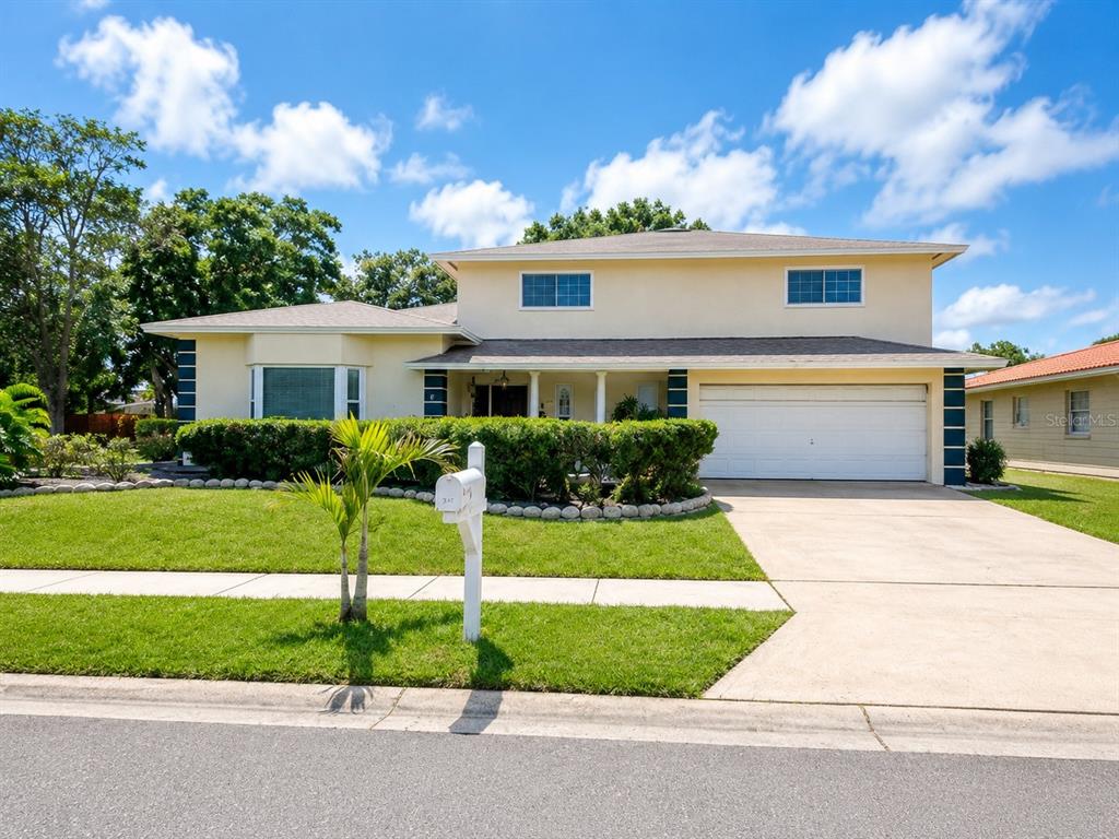 A two-story house with a beige exterior, a white garage door, and a front lawn — 3146 CARLOS DRIVE, DUNEDIN, FL