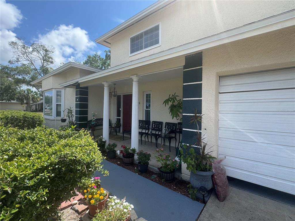 A house exterior features a covered front porch with white columns and a garage door — 3146 CARLOS DRIVE, DUNEDIN, FL