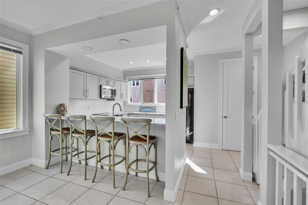 A kitchen with white cabinets, granite countertops, and four bar stools at a breakfast counter — 848 EVERGREEN WAY, LONGBOAT KEY, FL