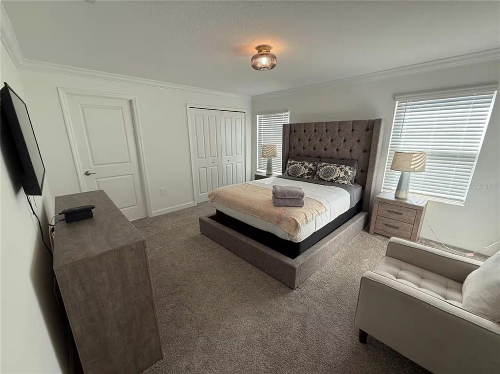 A bedroom features a tufted gray bed, matching nightstands, a dresser, and a beige armchair — 2669 READING TRAIL, KISSIMMEE, FL