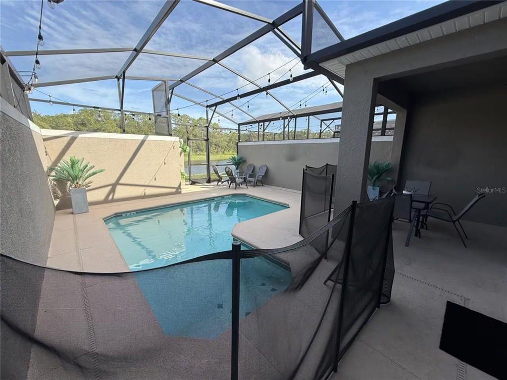 A screened-in pool patio features a small swimming pool, safety fence, and outdoor seating area — 2669 READING TRAIL, KISSIMMEE, FL