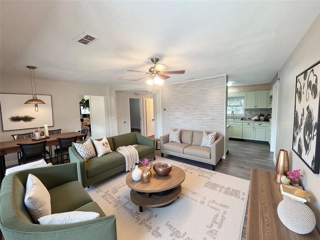 A living room with green and beige sofas, a round coffee table, and an open kitchen — 512 GREEN CIRCLE, FORT MEADE, FL