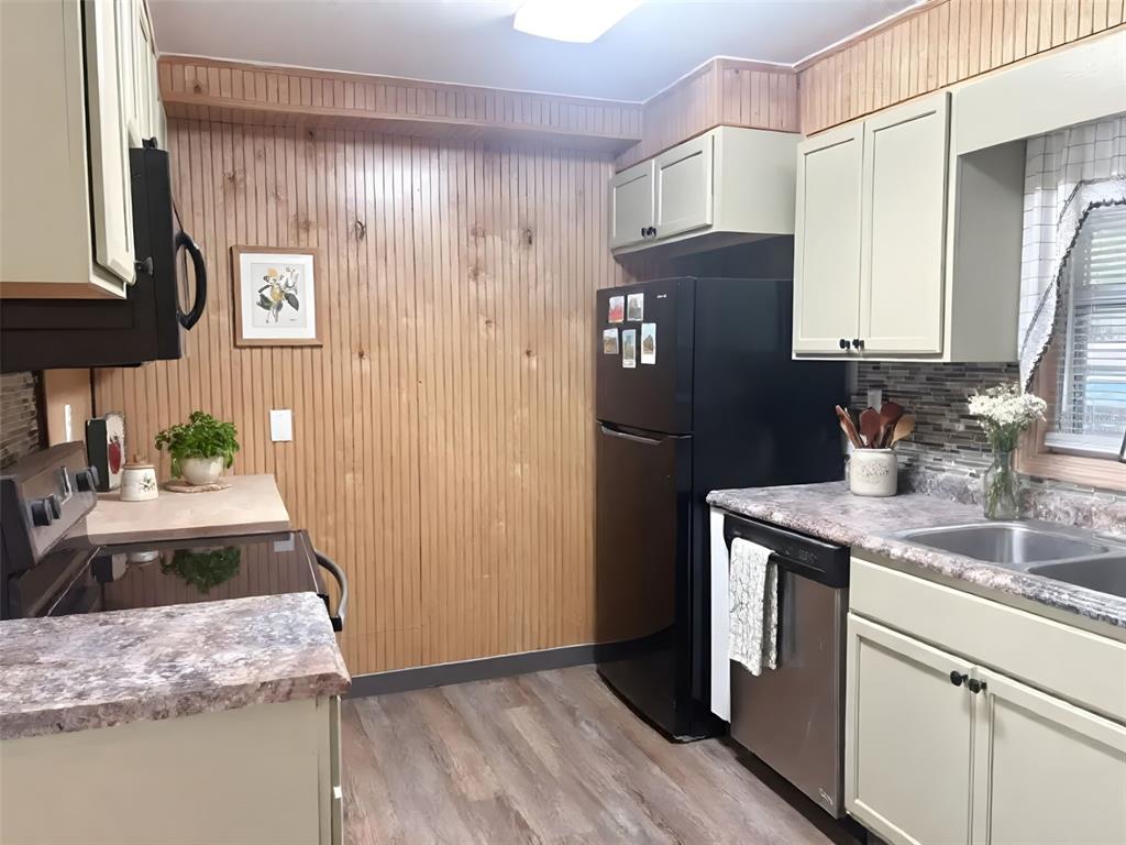 A kitchen features light green cabinets, wood-paneled walls, black appliances, and a laminate countertop — 512 GREEN CIRCLE, FORT MEADE, FL