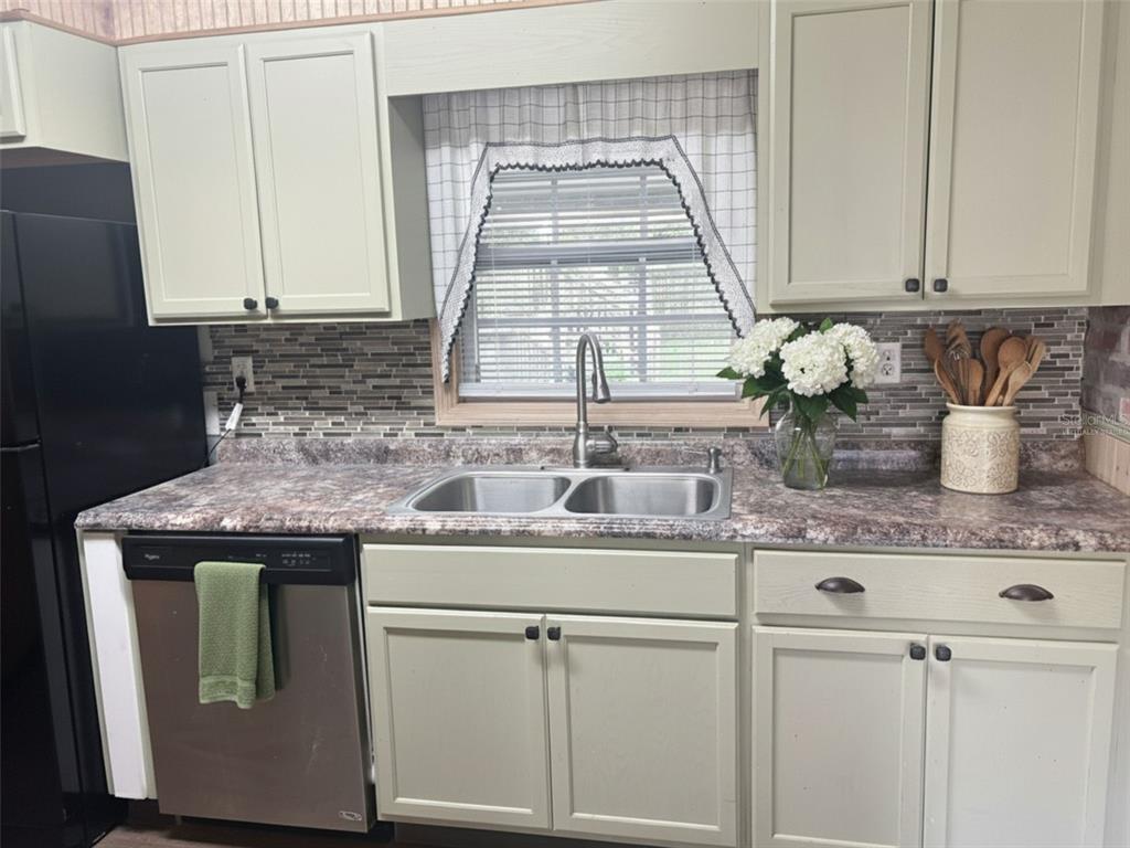 A kitchen features light green cabinets, a patterned laminate countertop, and a stainless steel sink — 512 GREEN CIRCLE, FORT MEADE, FL