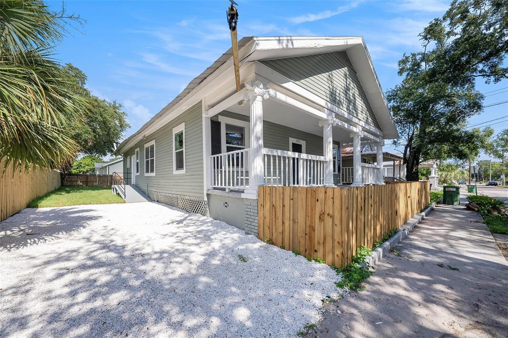 A light green house with a front porch and gravel driveway sits next to a sidewalk — 2920 N 17TH STREET, TAMPA, FL