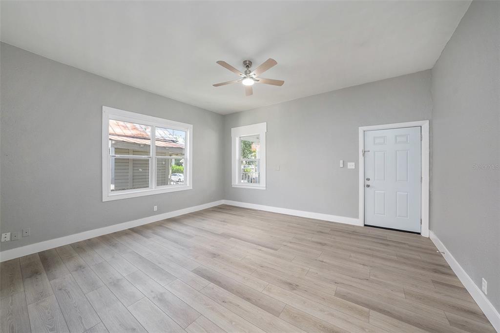 An empty room features gray walls, light wood-look flooring, a ceiling fan, and two windows — 2920 N 17TH STREET, TAMPA, FL