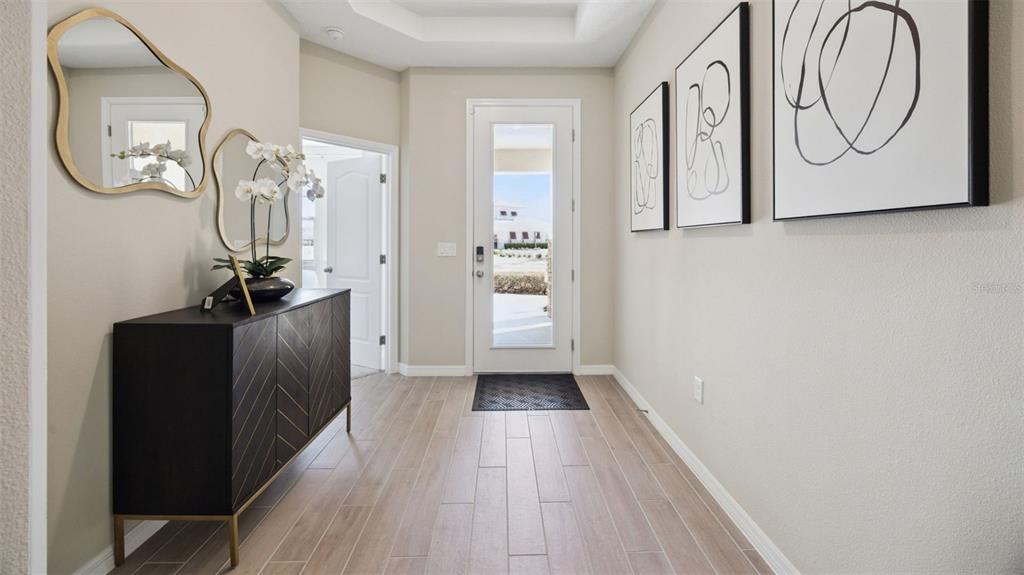 A bright entryway features a dark wood console table, two mirrors, and light-colored tile flooring — 3060 KINGSMAN TRAIL, ORMOND BEACH, FL