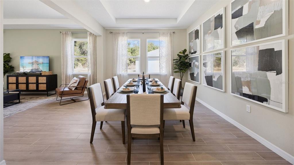 A dining room features a long wooden table, upholstered chairs, and large abstract wall art — 3060 KINGSMAN TRAIL, ORMOND BEACH, FL