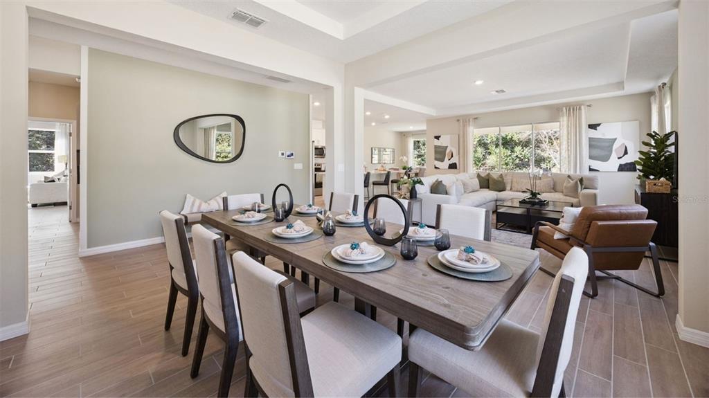 A dining room with a wooden table and chairs opens into a living area — 3060 KINGSMAN TRAIL, ORMOND BEACH, FL