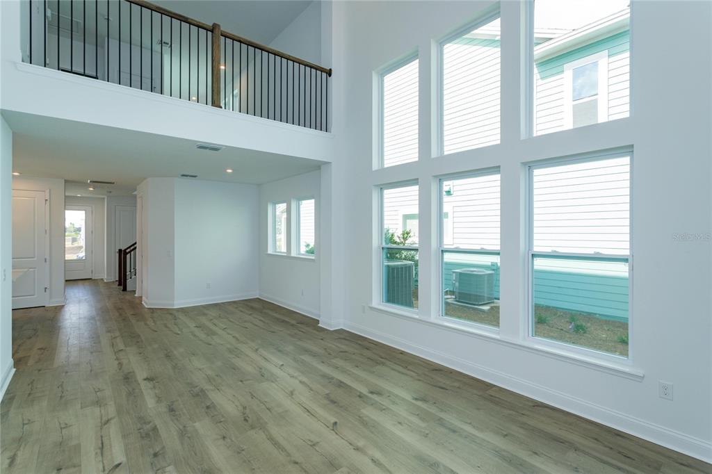 A bright living room features high ceilings, large windows, and light wood-look flooring — 6521 ROVER WAY, ST CLOUD, FL