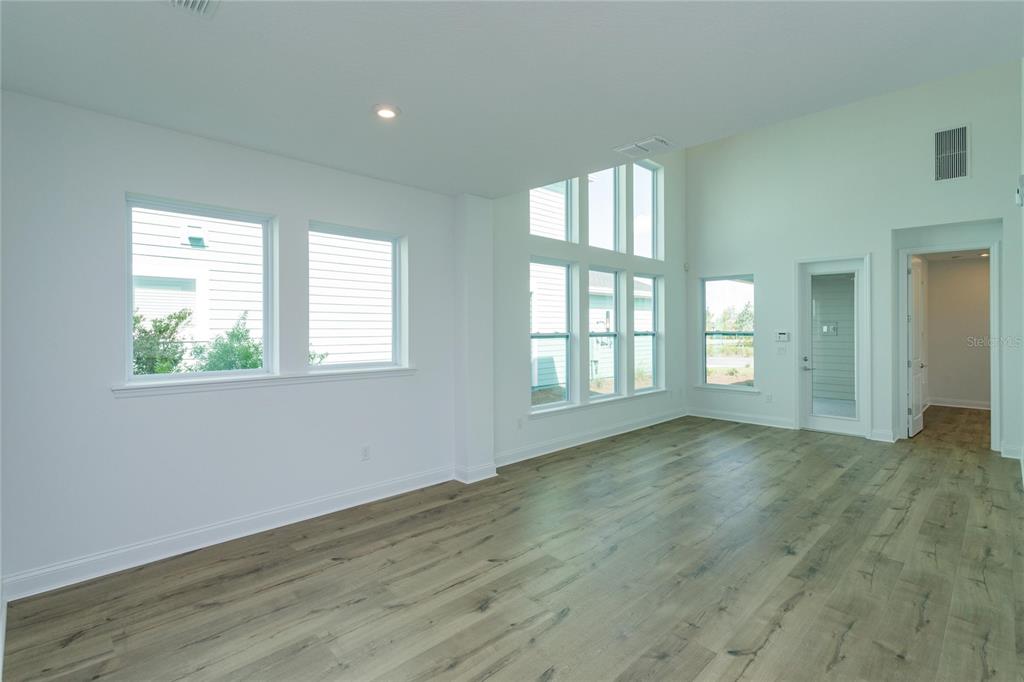 An empty room with light wood-look flooring, white walls, and large windows — 6521 ROVER WAY, ST CLOUD, FL