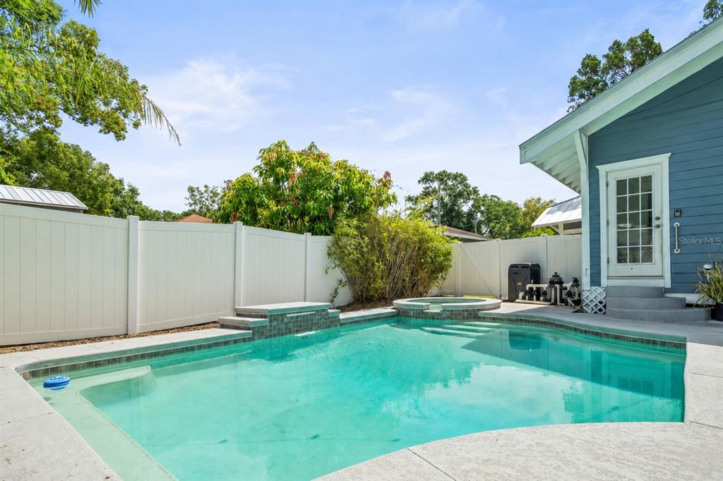 A backyard features a swimming pool with an attached spa and a white privacy fence — 7002 N CAMERON AVENUE, TAMPA, FL