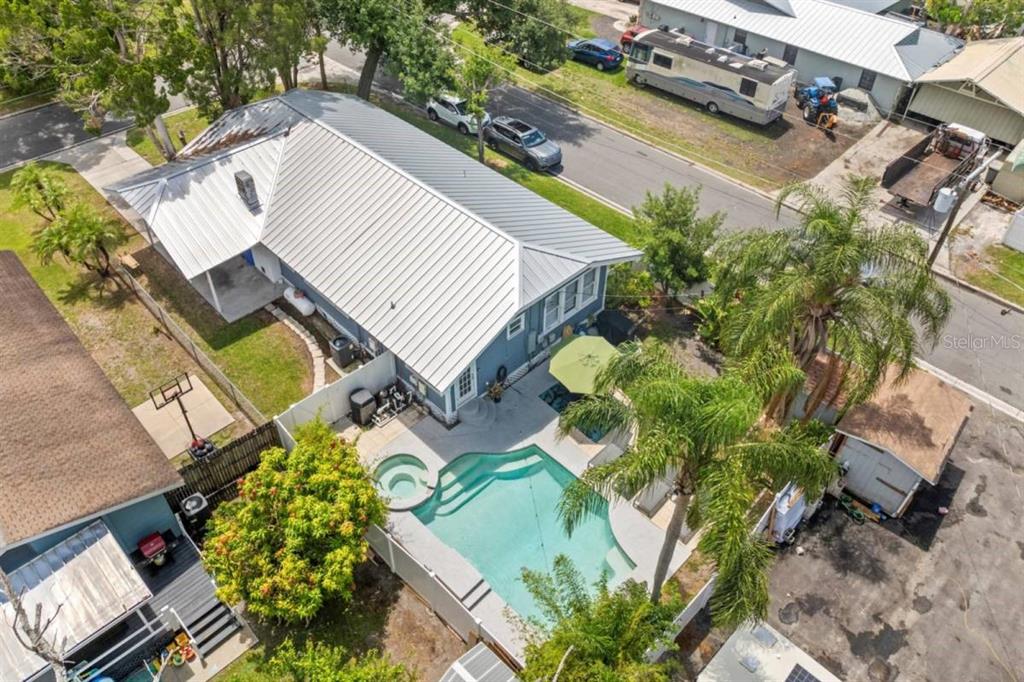 An aerial view of a house with a metal roof, swimming pool, and backyard patio — 7002 N CAMERON AVENUE, TAMPA, FL