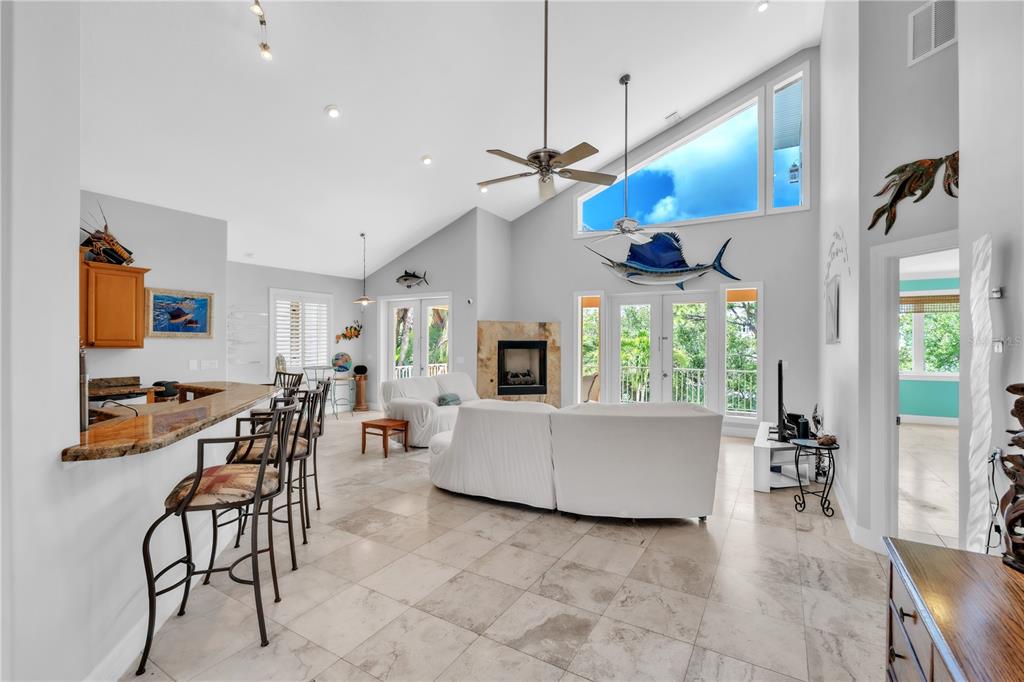 A spacious living room with vaulted ceilings, tile floors, a fireplace, and a breakfast bar — 1508 BOWLEES COVE, BRADENTON, FL