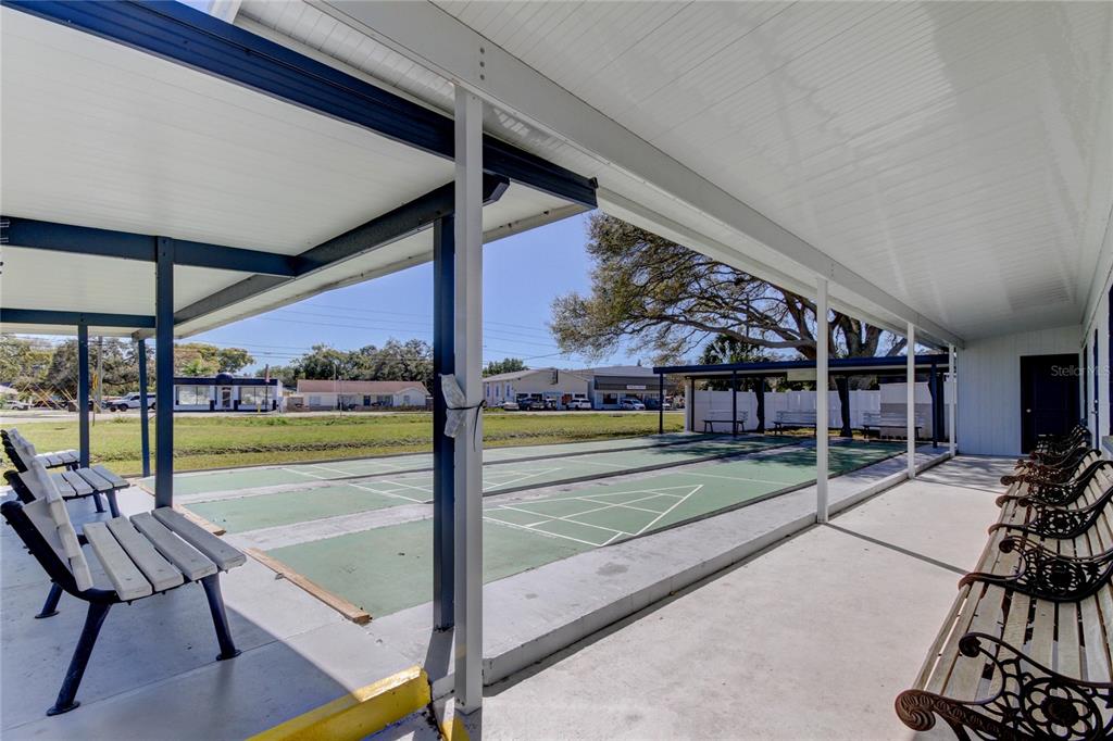 A covered outdoor shuffleboard court features multiple benches and a concrete patio area — 4776 66TH LANE N UNIT 12, ST PETERSBURG, FL