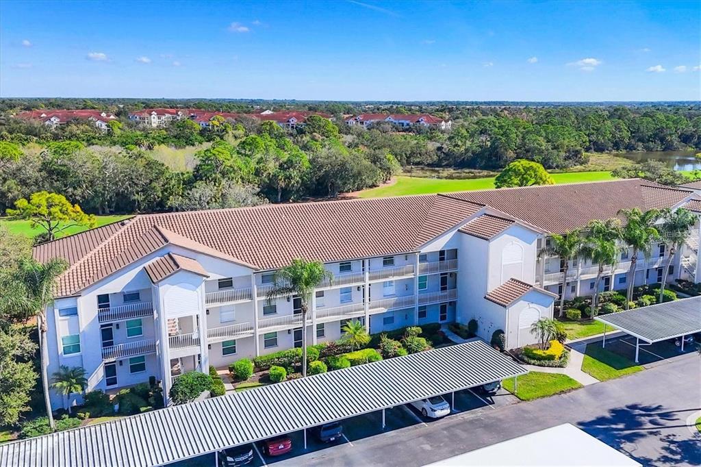 An aerial view of a multi-story apartment building with a covered parking area — 8735 OLDE HICKORY AVENUE UNIT 8105, SARASOTA, FL