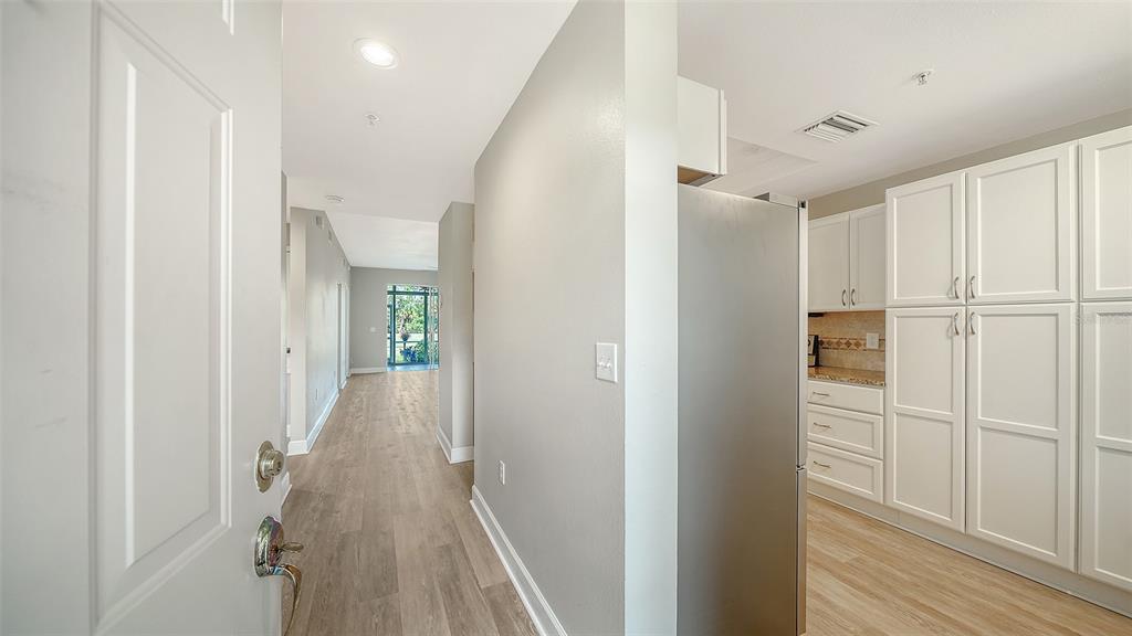A view from an entryway looking toward a hallway and a kitchen with white cabinetry — 8735 OLDE HICKORY AVENUE UNIT 8105, SARASOTA, FL