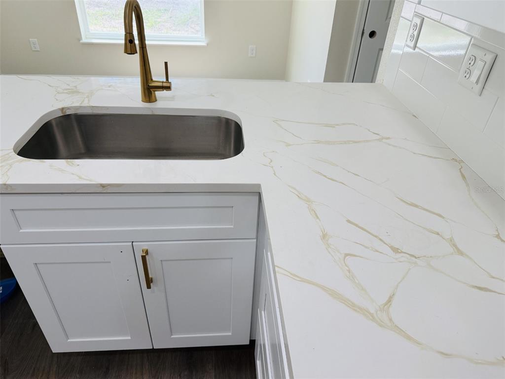 A kitchen features white cabinets, a gold faucet, and a white countertop with gold veining — 13475 CANYON SWALLOW ROAD, WEEKI WACHEE, FL