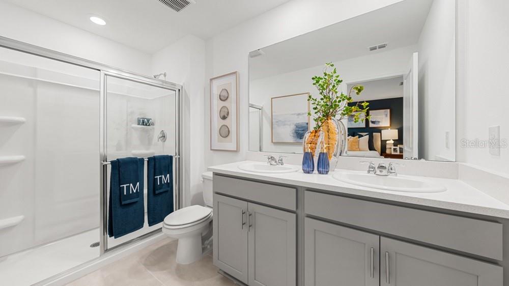 A modern kitchen features gray cabinets, white countertops, stainless steel appliances, and a central island — 7117 PINELIT COVE, NOKOMIS, FL
