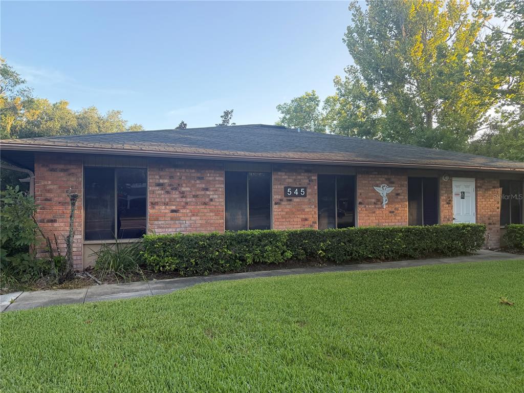 A single-story brick building with a dark shingled roof and a manicured front lawn — 545 W GRANADA BOULEVARD, ORMOND BEACH, FL