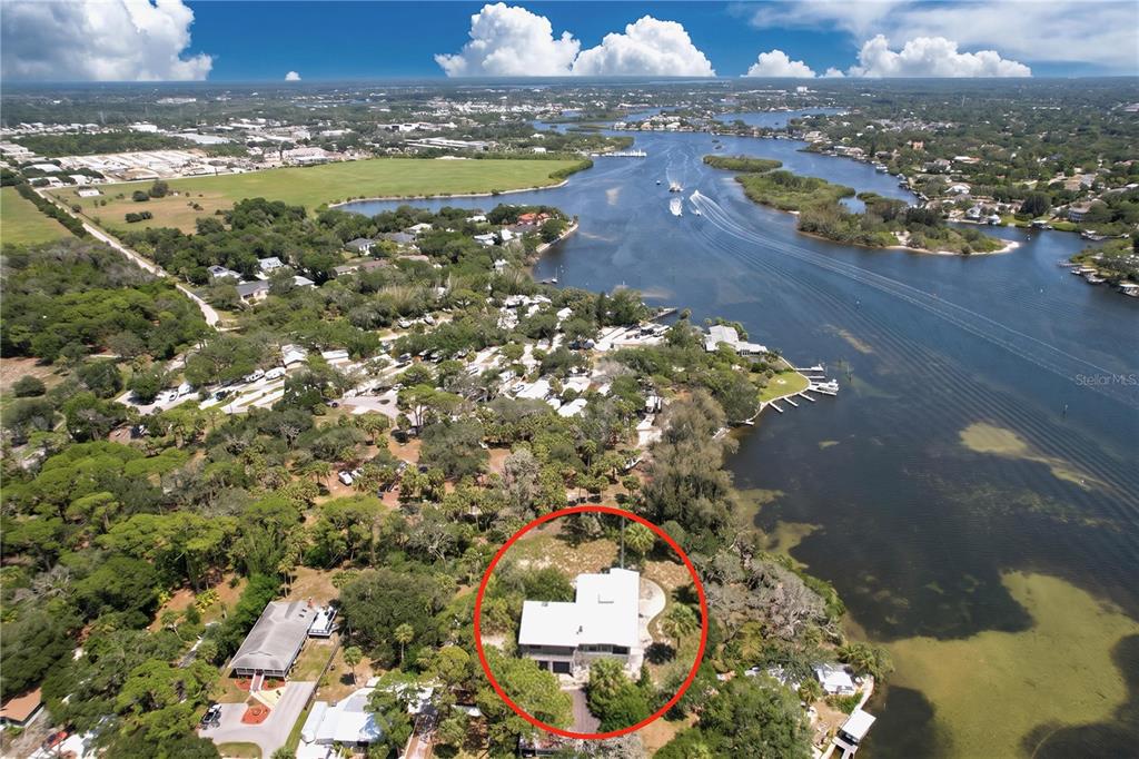 An aerial view shows a house with a white roof situated on a wooded lot — 1275 MICKLER LANE, TARPON SPRINGS, FL