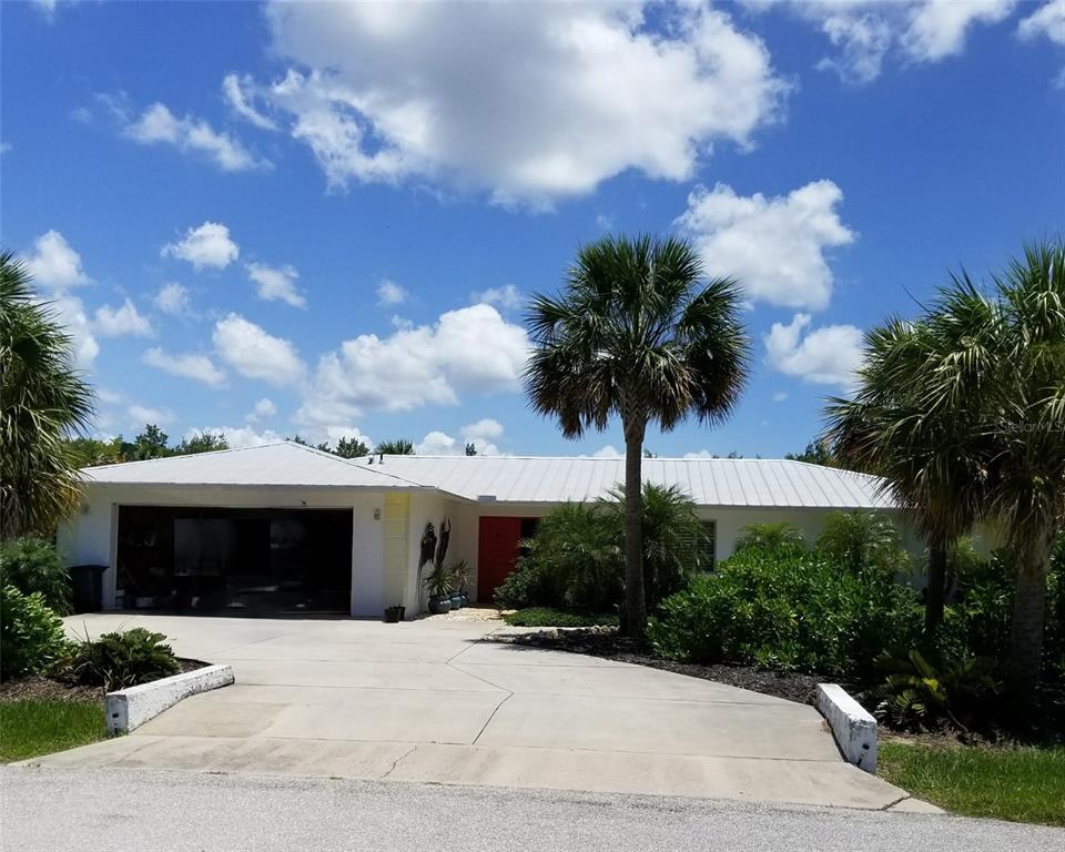 A single-story house with a white metal roof, a two-car garage, and a red door — 120 BARRACUDA DRIVE, PLACIDA, FL