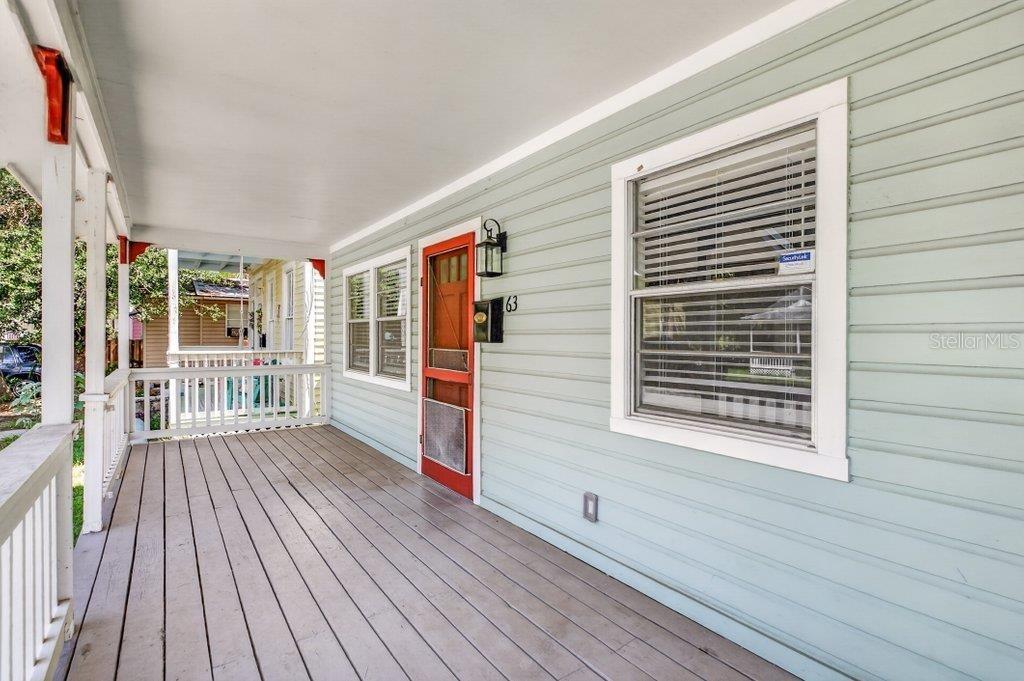 A covered wooden porch with light green siding and a red screen door — 63 DUMAS STREET, ST AUGUSTINE, FL