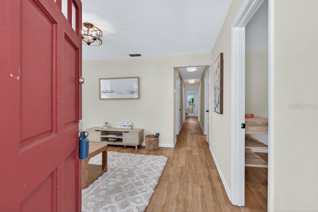 An open red door reveals a living room with light wood flooring and a hallway — 63 DUMAS STREET, ST AUGUSTINE, FL