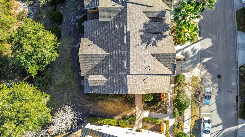 An aerial view shows the shingled roof of a residential building and adjacent street — 885 ASSEMBLY COURT, REUNION, FL