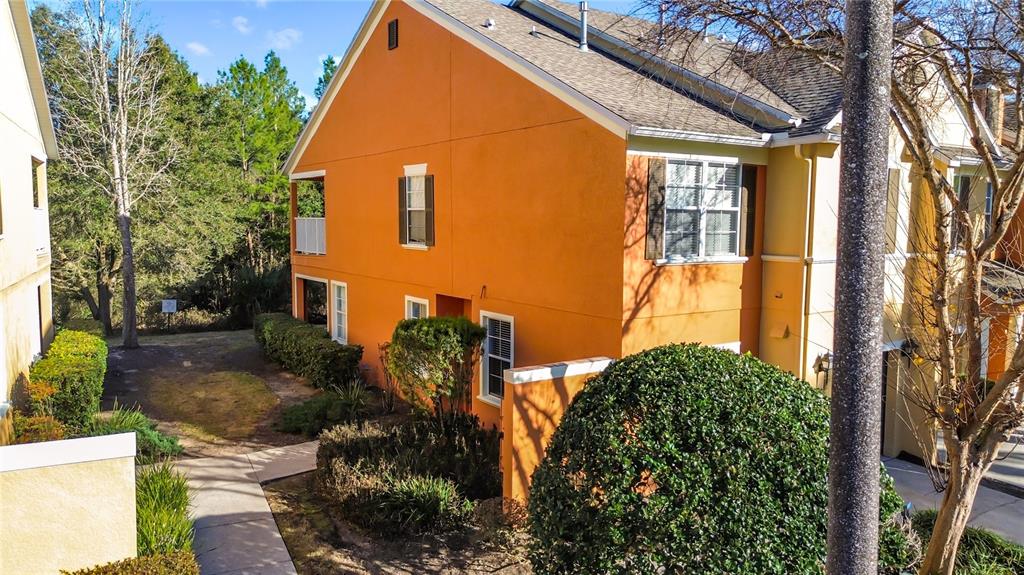 An exterior view of an orange multi-story townhouse with a sidewalk and surrounding landscaping — 885 ASSEMBLY COURT, REUNION, FL