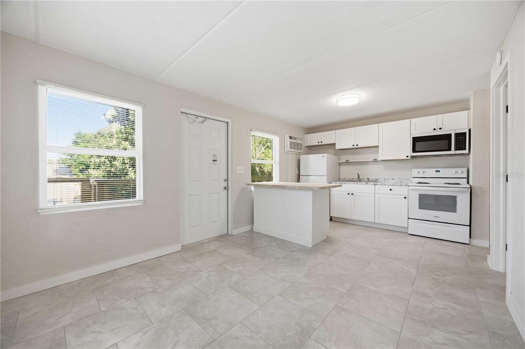 A kitchen with white cabinets, white appliances, a small island, and light-colored tile flooring — 419 GRAPEFRUIT AVENUE UNIT 2A, SEBRING, FL