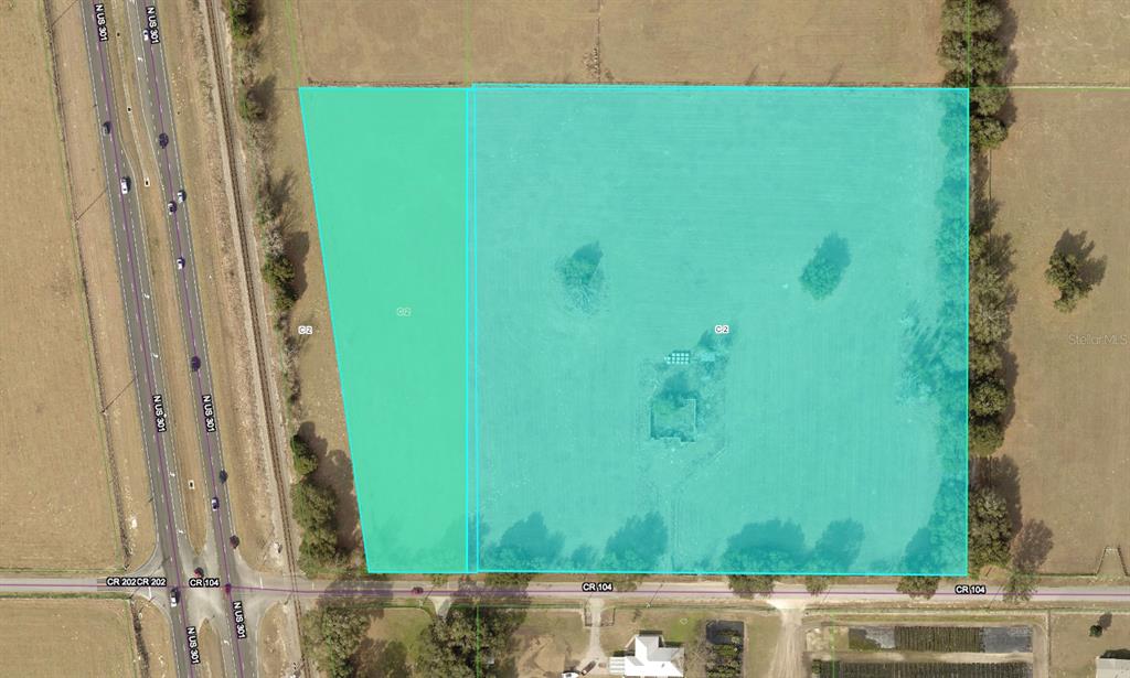 This aerial map shows two adjacent parcels of land highlighted in teal near a highway — 4040 COUNTY ROAD 104, OXFORD, FL