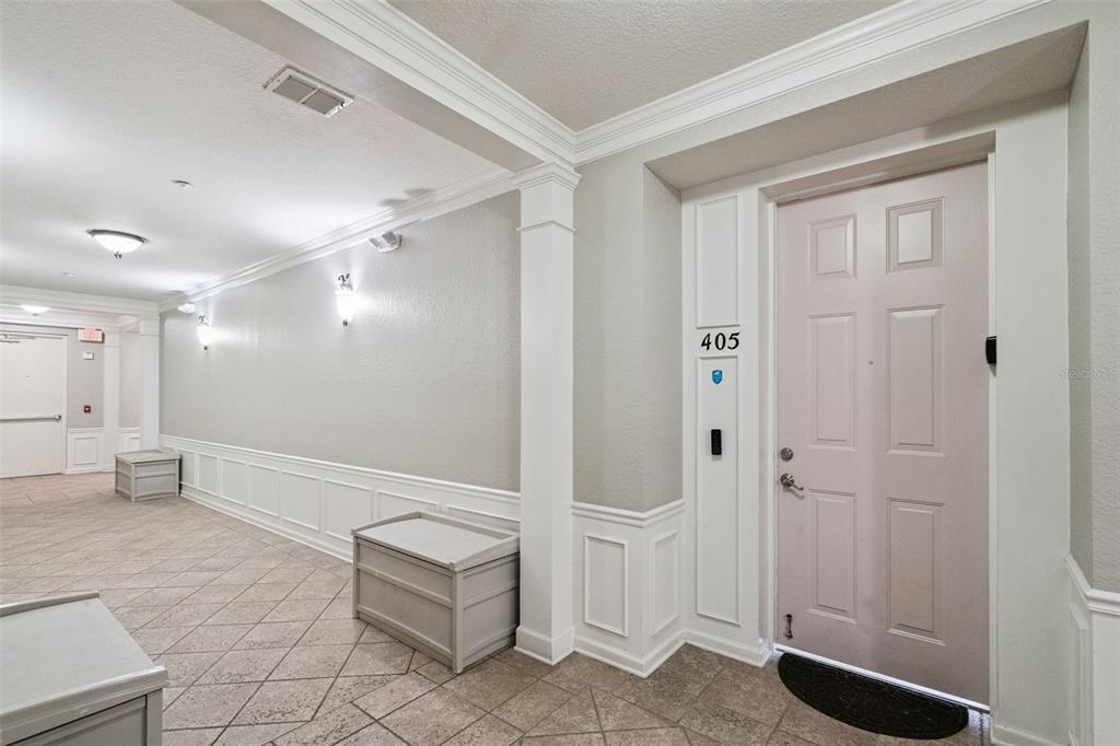 A hallway with tile flooring, white wainscoting, and a door labeled 405 — 4840 CAYVIEW AVENUE UNIT 405, ORLANDO, FL