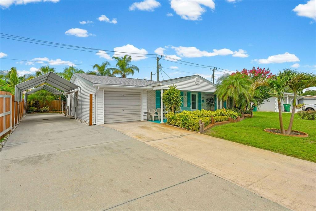 A single-story house with a concrete driveway, a metal carport, and a front lawn — 2545 EDNOR STREET, PORT CHARLOTTE, FL