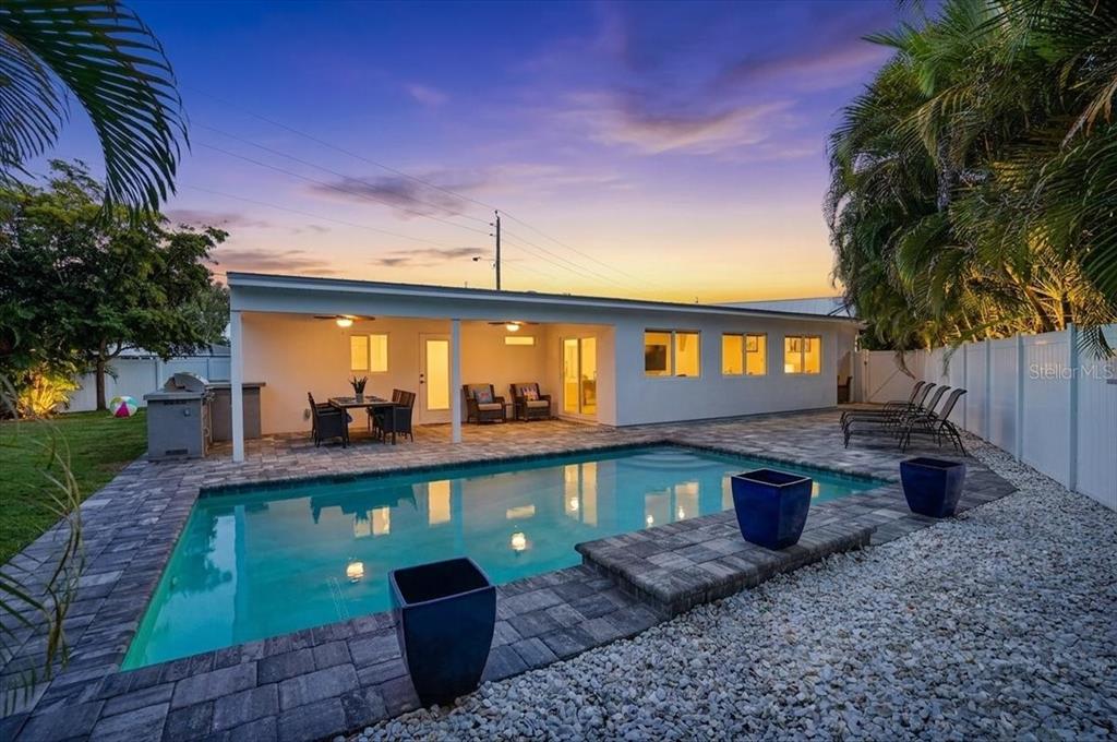A backyard features a rectangular swimming pool, a covered patio, and a white privacy fence — 2201 WEBBER STREET, SARASOTA, FL